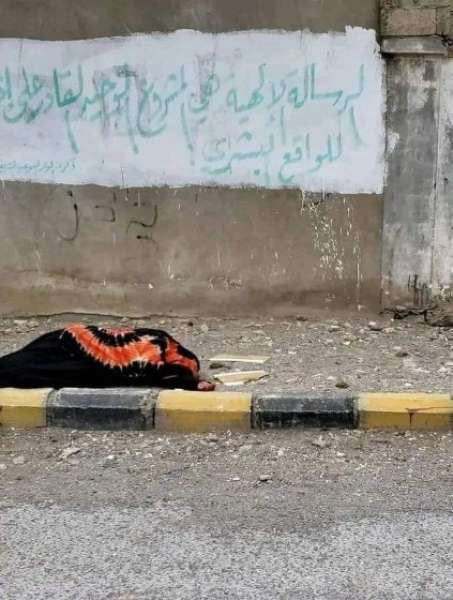 تجسيدا لمعاناة اليمنيين.. امرأة مسنة تنام في الشارع أمام لوحة جدارية للمليشيا الحوثية