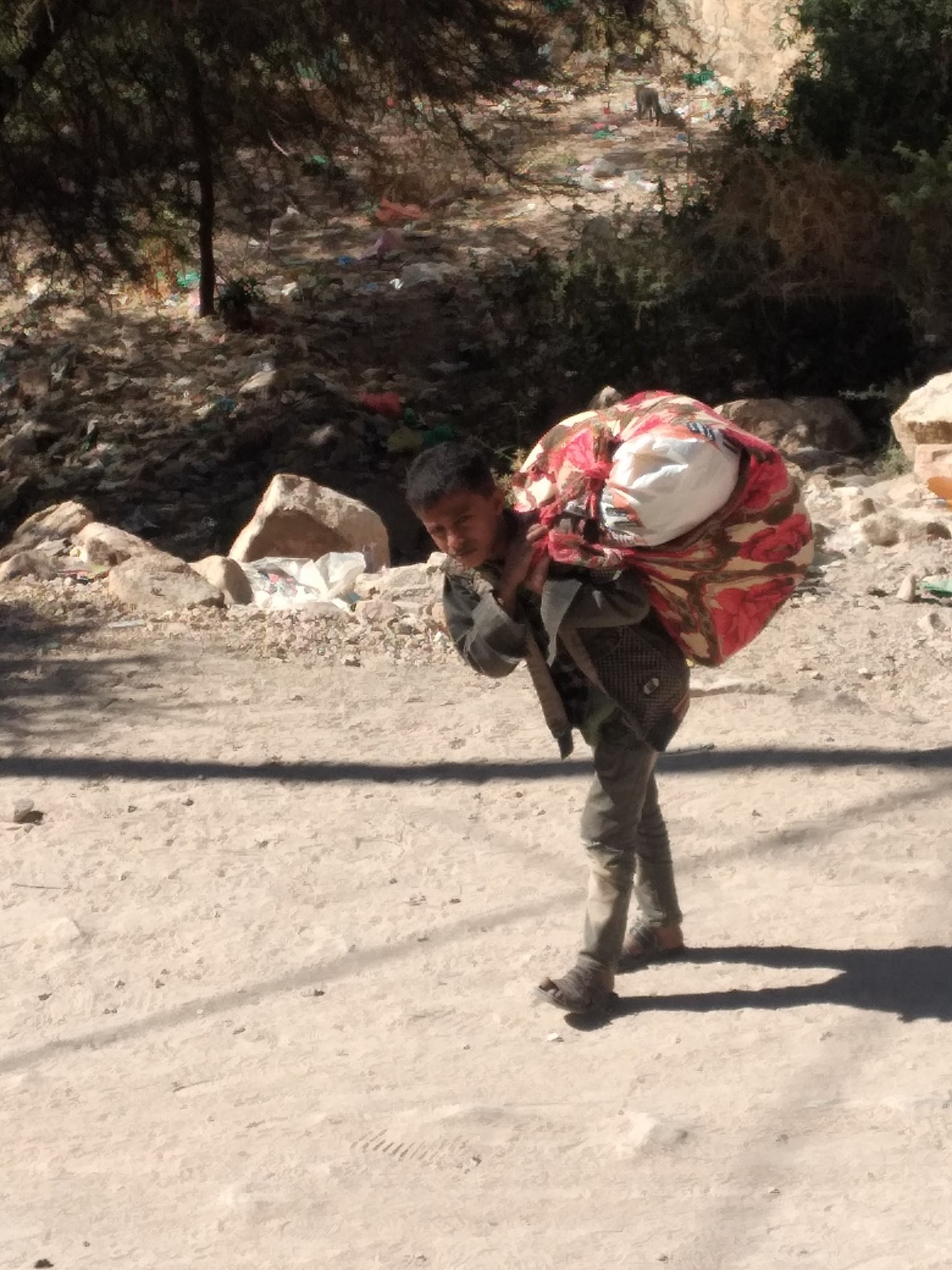 شاهد كيف ظهر طفل يمني بدكان متجول على ظهره .. صورة